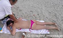 Namorada jovem dá uma massagem sem blusa na praia