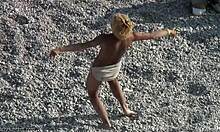 Забавна блондинка танцува наоколо в пясъка