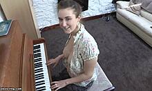 Játékos külsejű barna hajú lány hetyke mellekkel játszik a zongorán, félmeztelenül