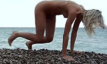 Si blonde berpose telanjang di pantai berbatang