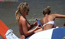 Blonde veninder viser deres bryster og varme kroppe på en strand