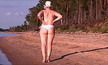 امرأة ناضجة حسي تتباهى بمنحنياتها في ملابس سباحة بيضاء.