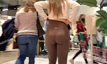 Een sexy blonde tiener in bruine leggings pronkt met haar grote kont